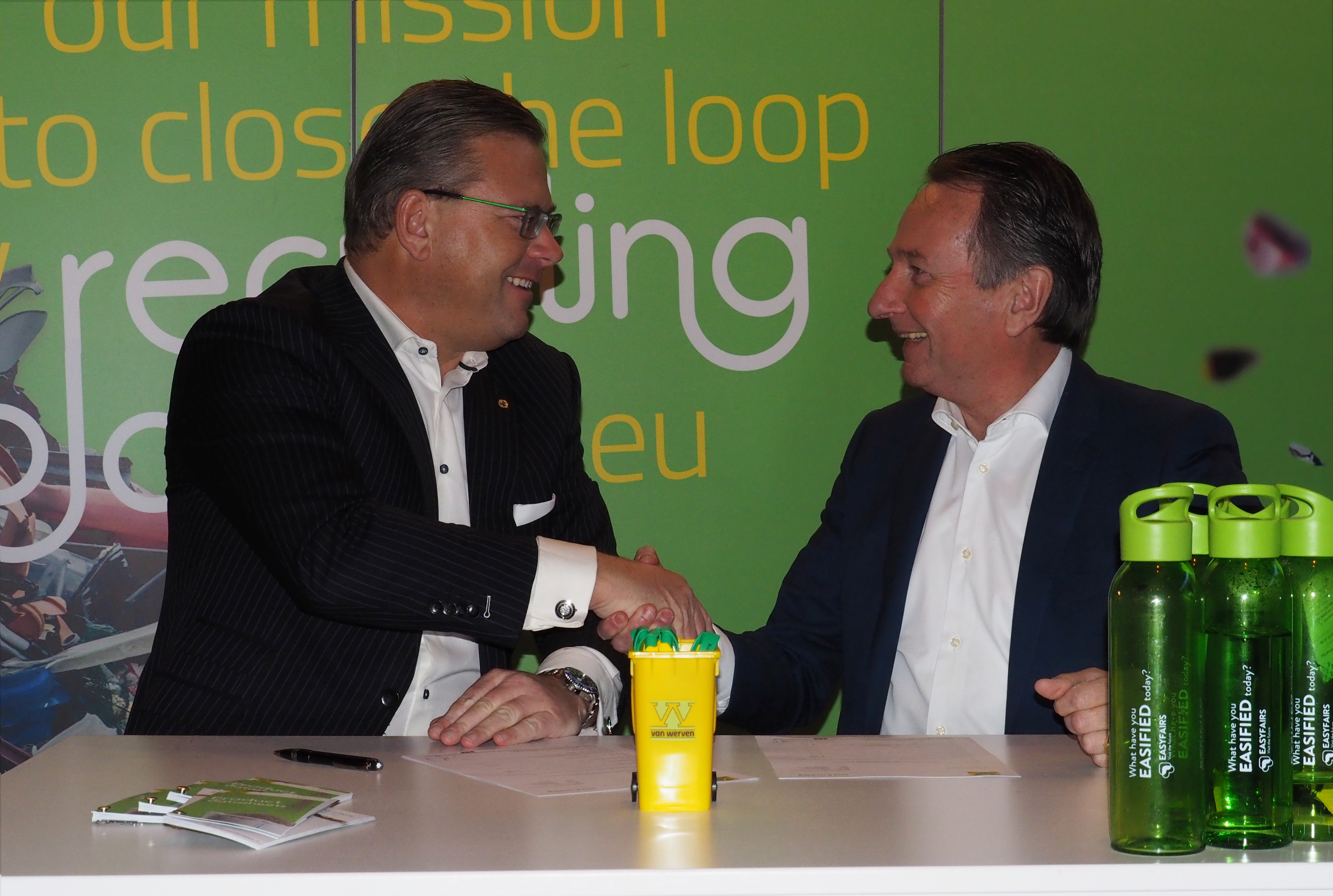 Handdruk bij de contractondertekening op de vakbeursstand, met een miniatuur Van Werven-container op tafel
