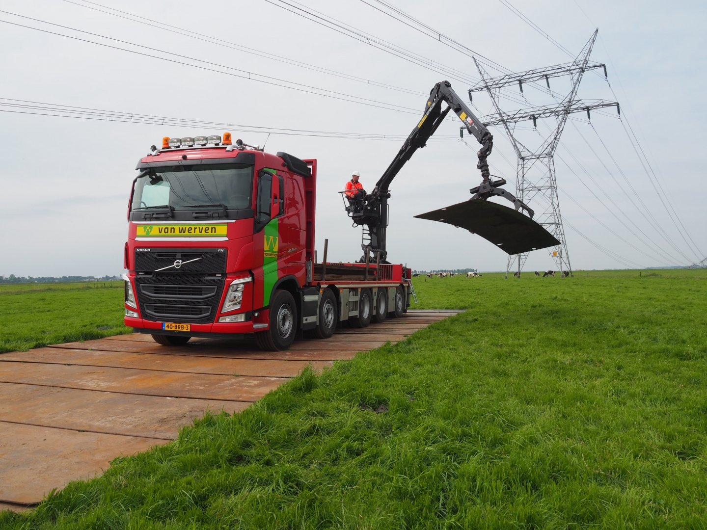 Vrachtwagen met autolaadkraan van Van Werven legt stalen rijplaten in een weiland