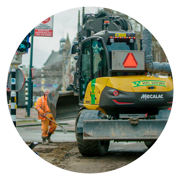 Een Mecalac graafmachine van Van Werven bij straatwerkzaamheden, met een stratenmaker met schep ernaast
