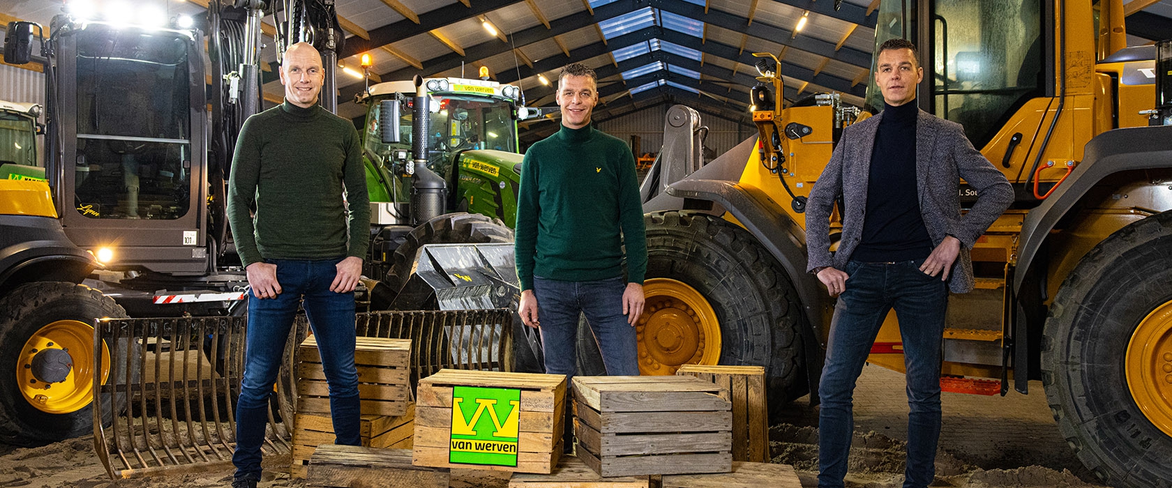 De drie broers Van Werven staan tussen de machines in de loods, rond een stapel houten kratten met het Van Werven-logo