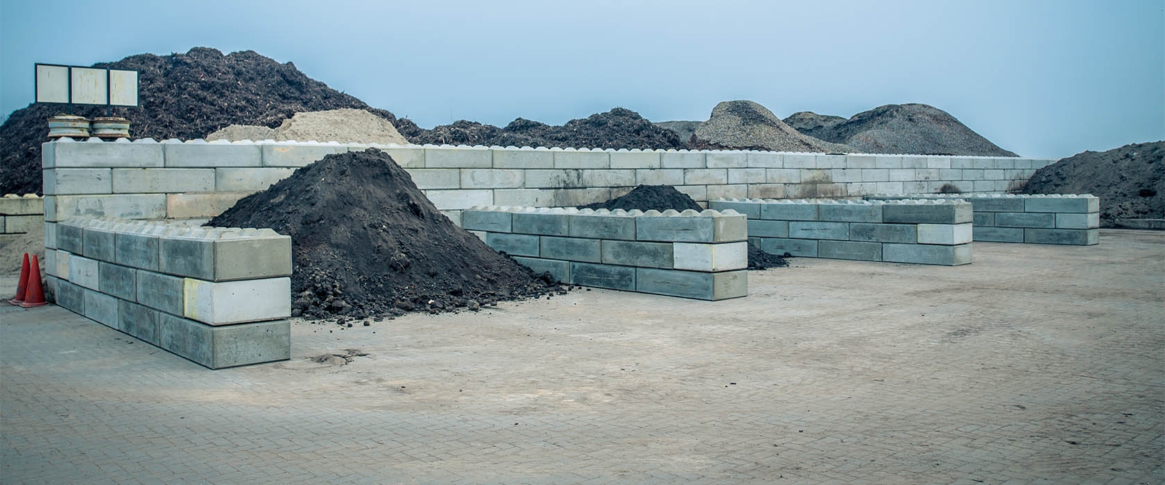 Opslagvakken van betonstapelblokken op een depot van Van Werven, gevuld met grond, compost en granulaat