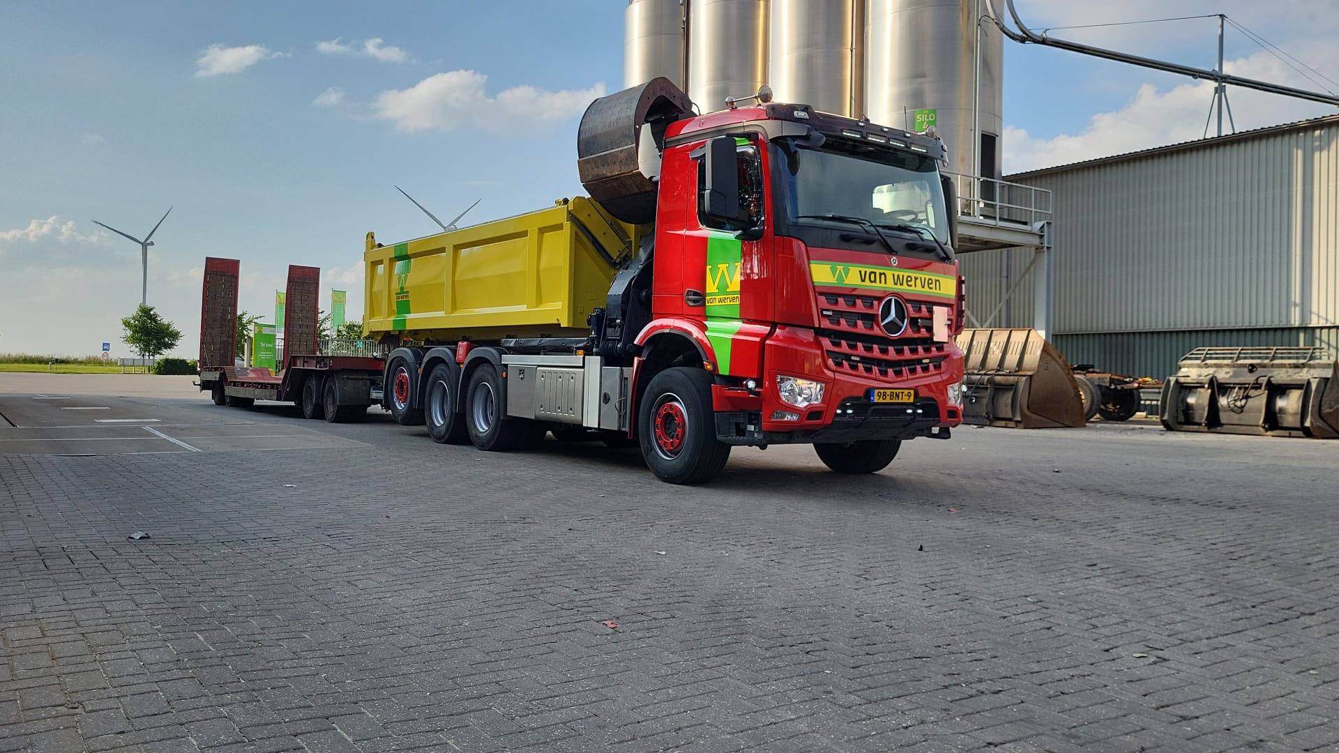 Vrachtwagen van Van Werven met autolaadkraan en gele container bij de silo’s