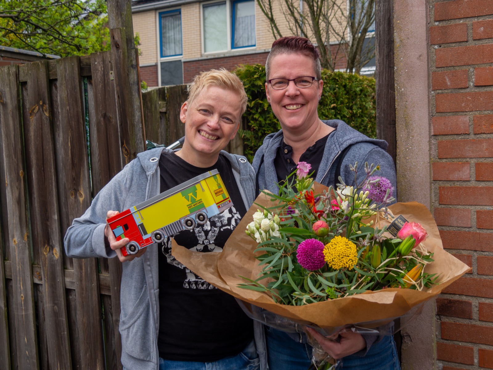 De twee vrouwen met het bloemboeket en het blikken Van Werven-vrachtwagentje