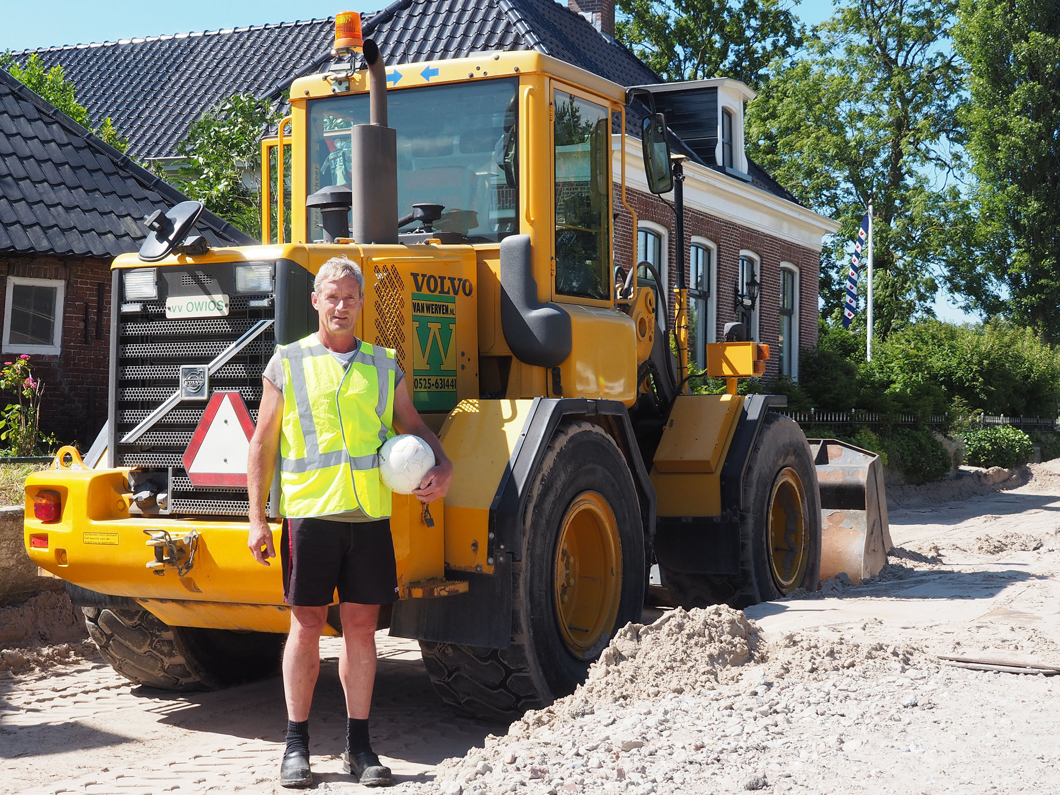 Machinist met voetbal voor zijn Volvo-shovel met OWIOS-logo