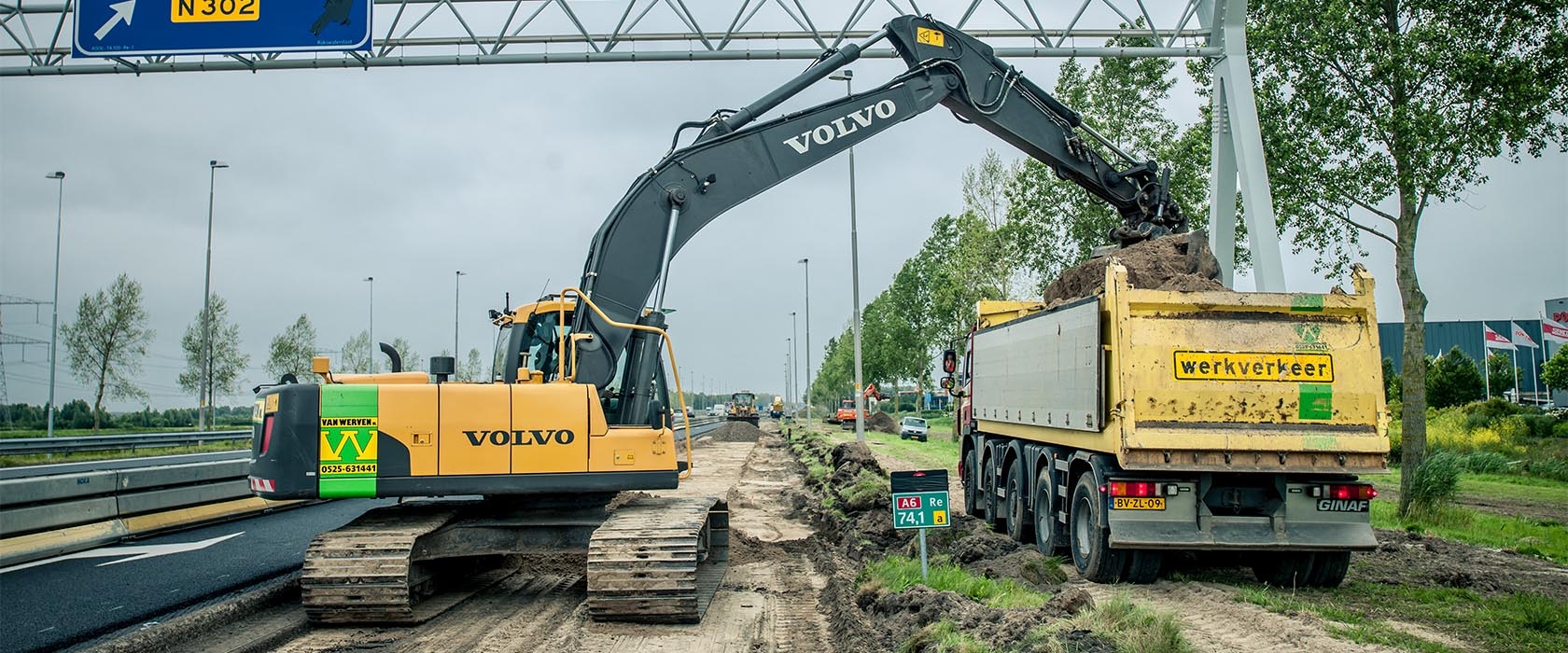 Een Volvo-graafmachine van Van Werven laadt grond in een kiepauto onder een portaal met het bord naar de N302