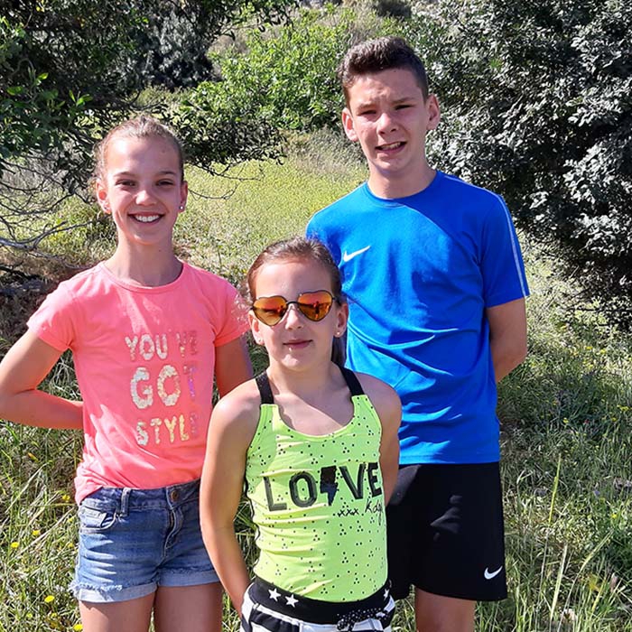 Drie kinderen poseren lachend voor het groen
