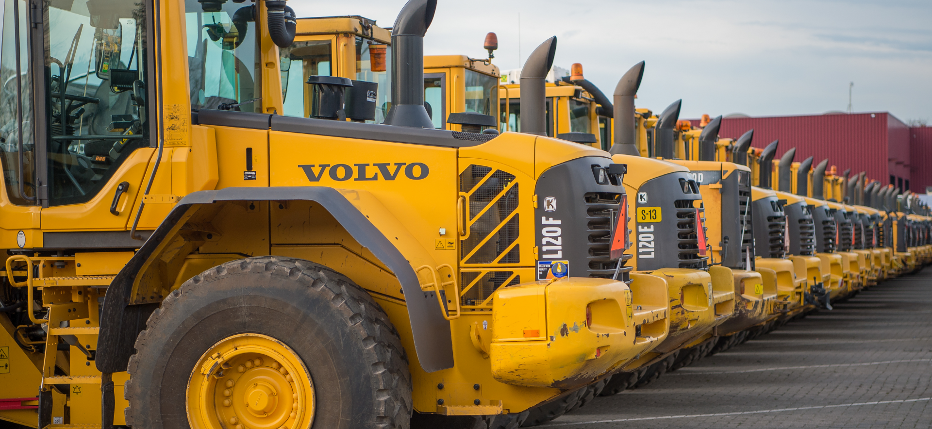 Lange rij gebruikte gele Volvo wielladers op het handelsterrein
