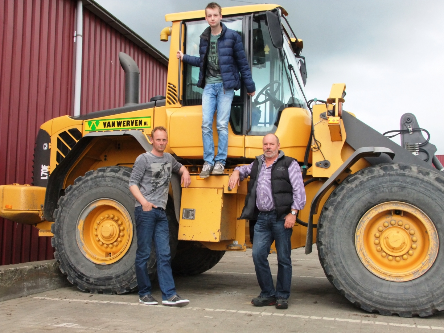 Drie generaties bij een Volvo-shovel van Van Werven: opa en vader ervoor, de zoon staand in de cabinedeur