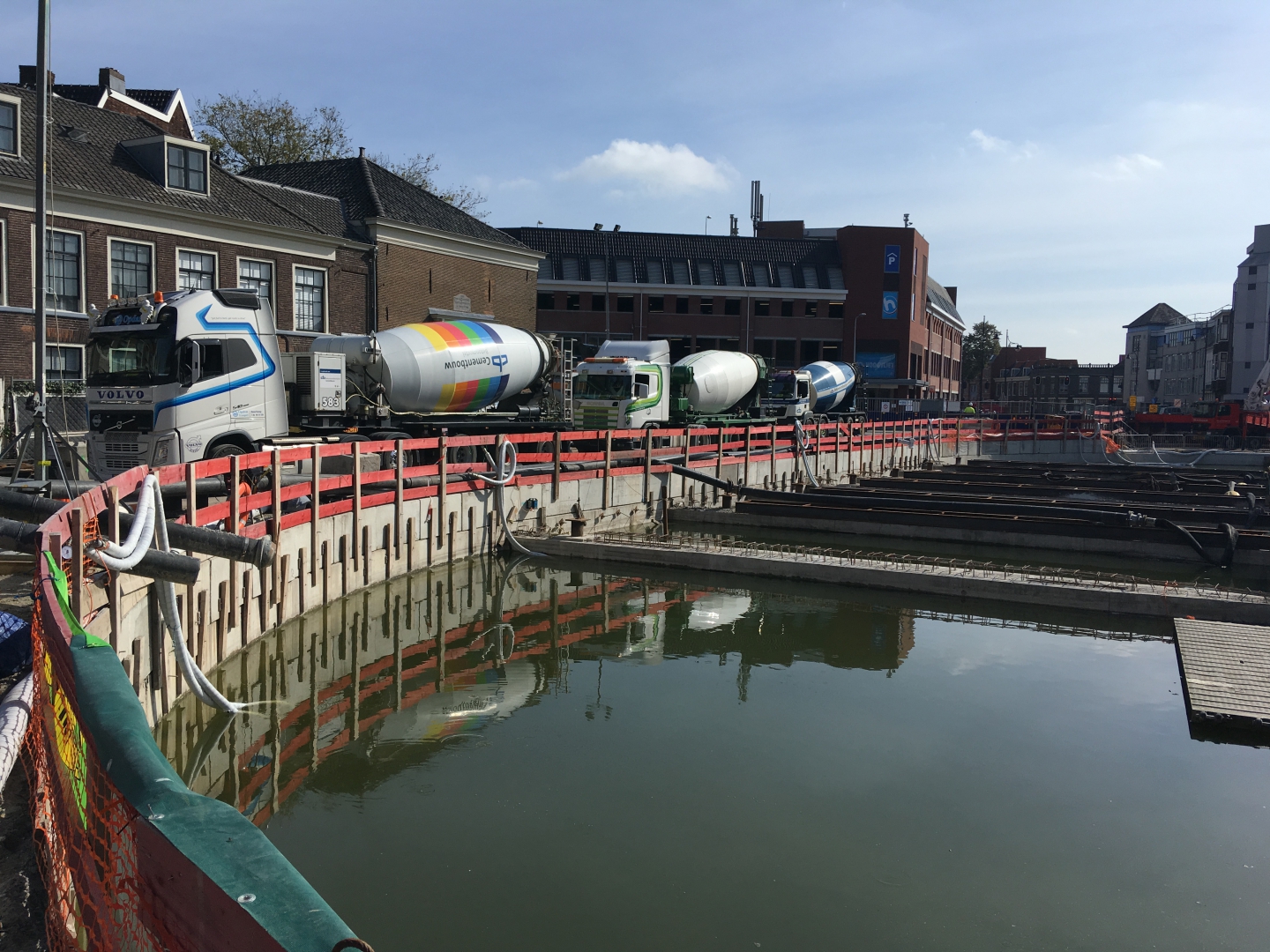 Betonmixers in de rij op de kuiprand voor het storten van het onderwaterbeton, het water nog in de kuip