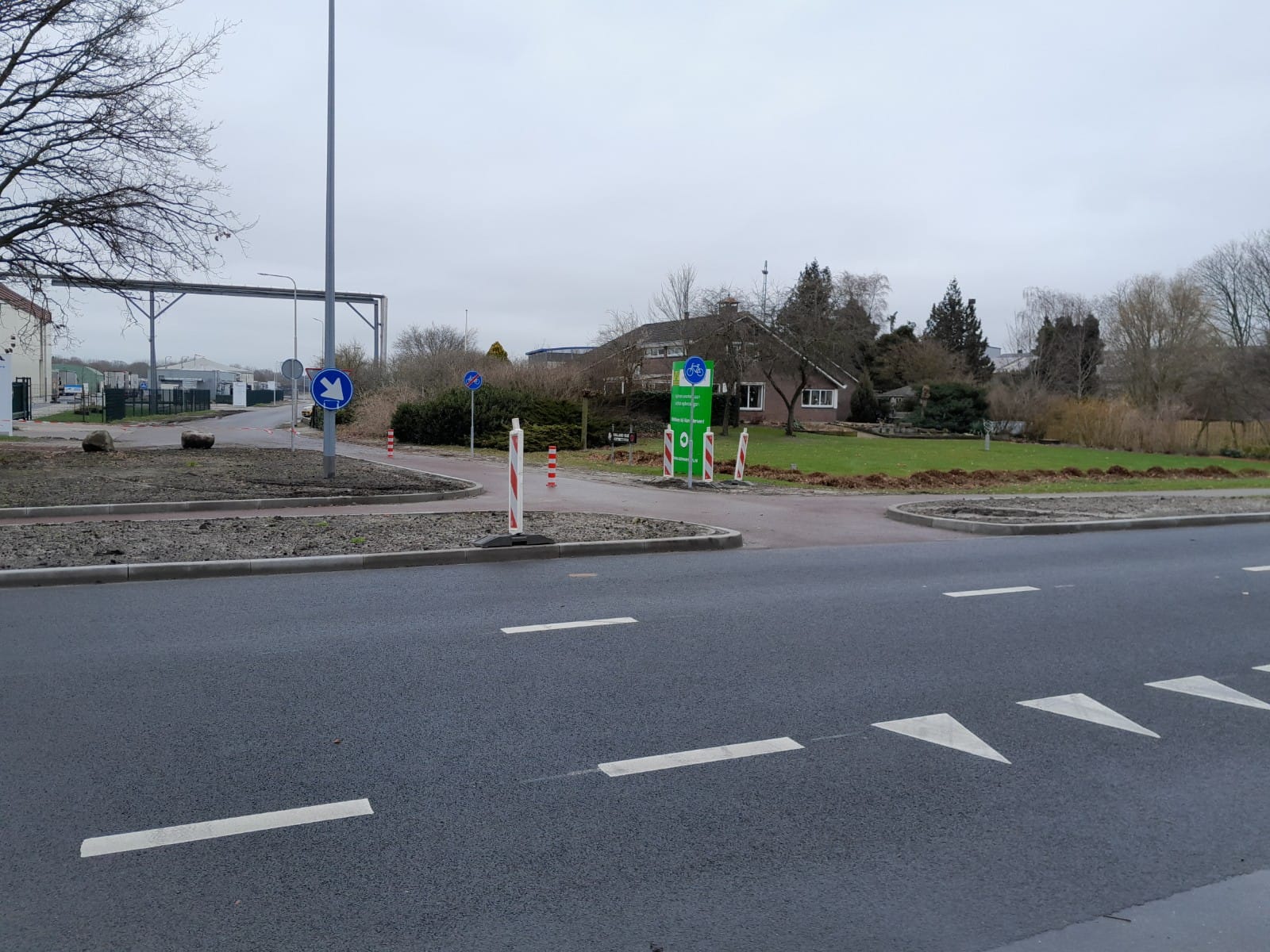 Twee foto's van de nieuwe inrit bij de rotonde aan de Coevorderweg, met verkeersborden en Van Werven-vlaggen