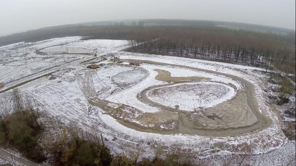 Luchtfoto van het licht besneeuwde werkterrein, met de contouren van de nieuwe waterpartijen in het zand