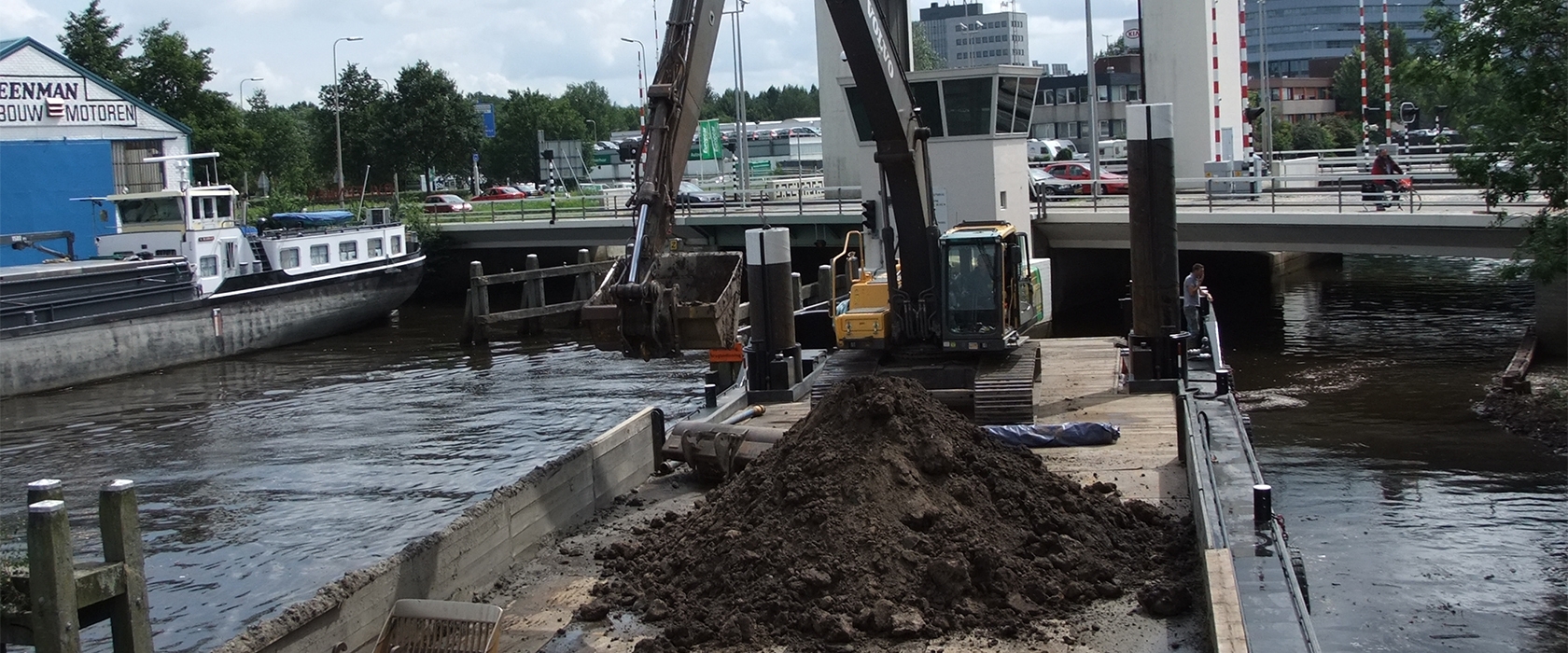 Graafmachine op een ponton baggert een gracht uit bij een brug