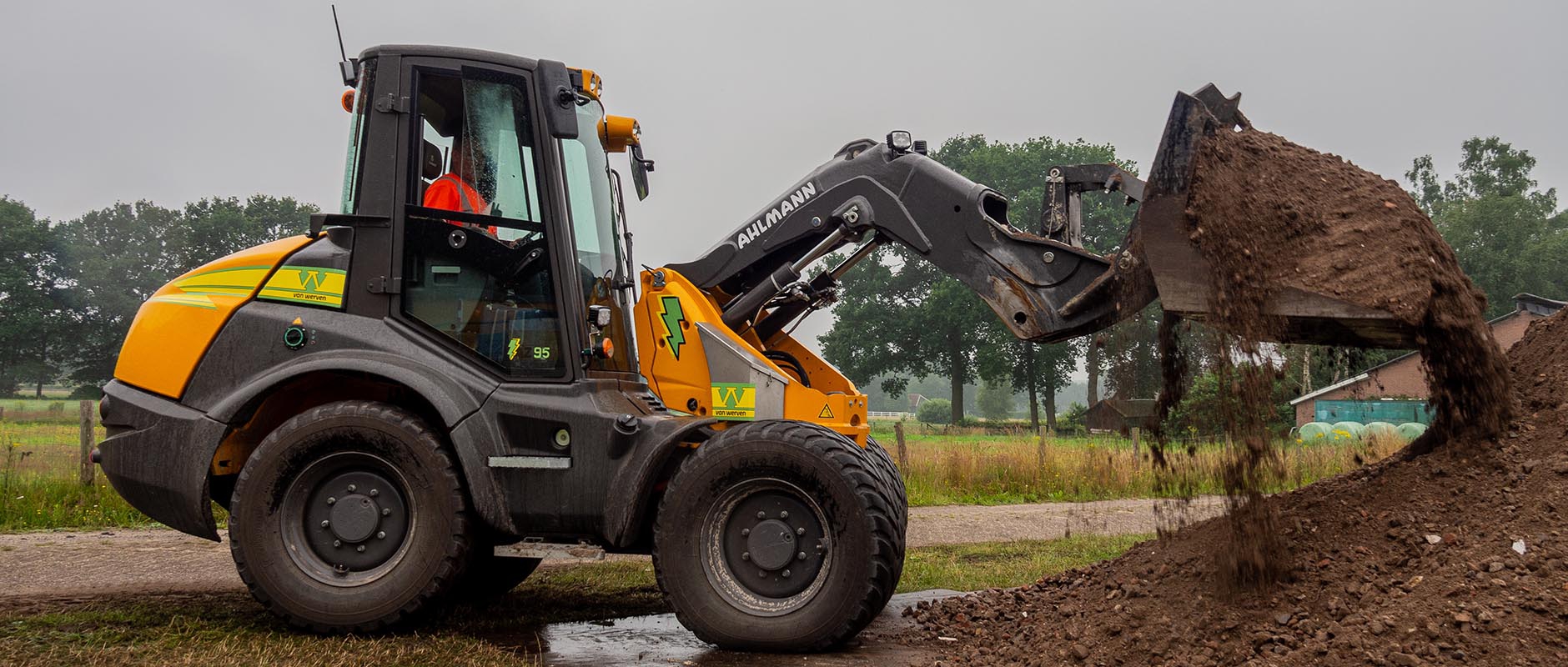 De elektrische Ahlmann AZ 95 shovel van Van Werven kiept een bak grond op een hoop