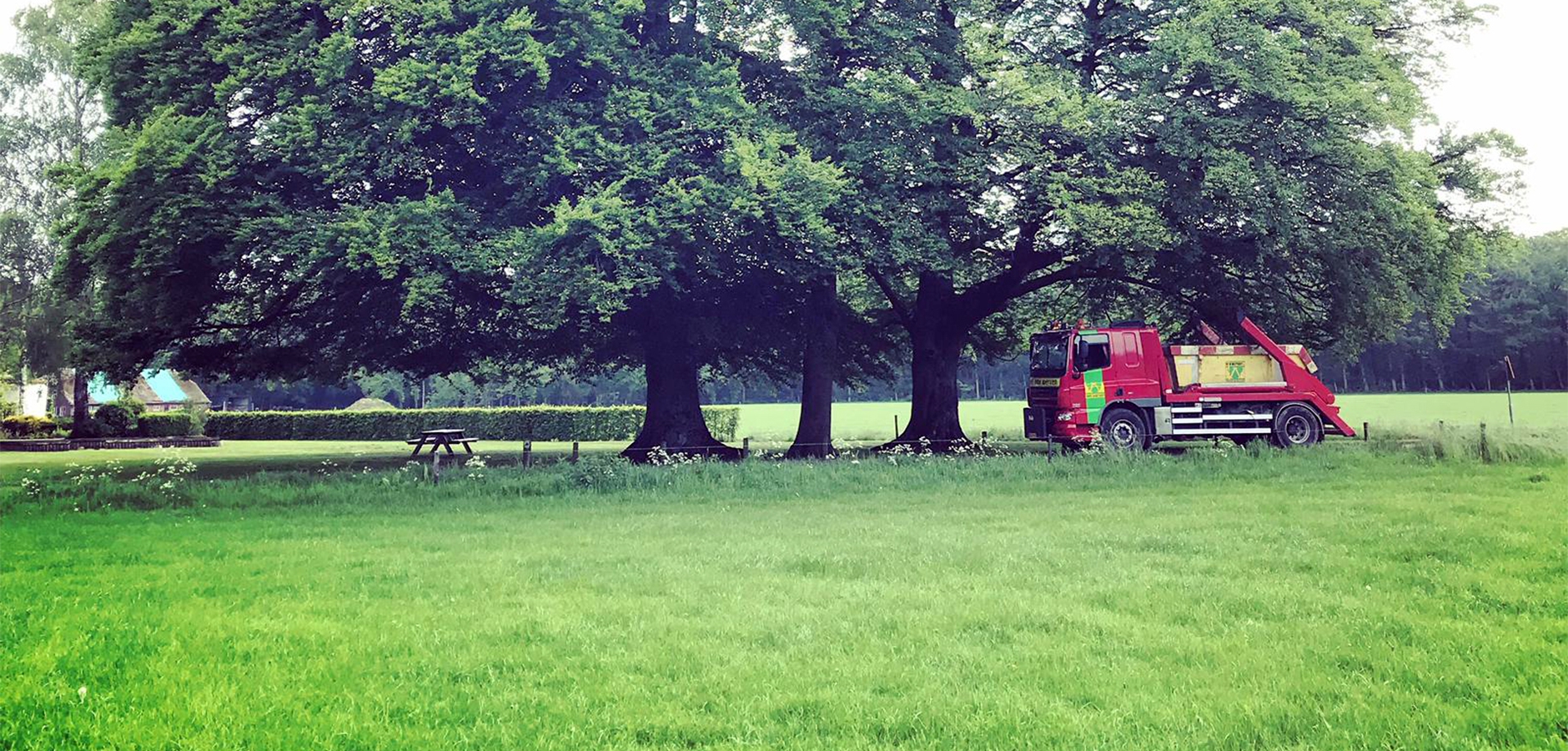 Portaalarmauto van Van Werven rijdt onder grote bomen langs een weiland