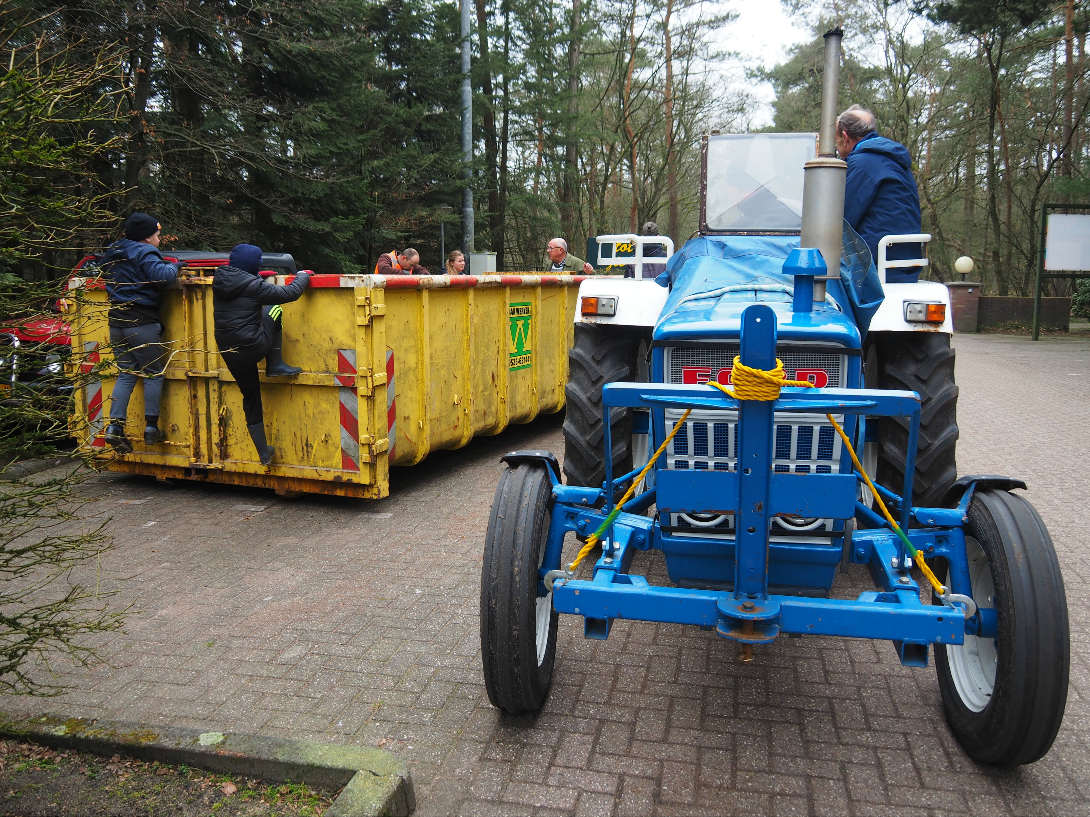 Vrijwilligers verzamelen zwerfafval in de Van Werven-container achter de blauwe Ford-tractor
