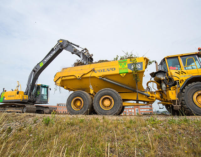 Rupskraan laadt groen en grond in een Volvo-dumper langs de Kamperlijn