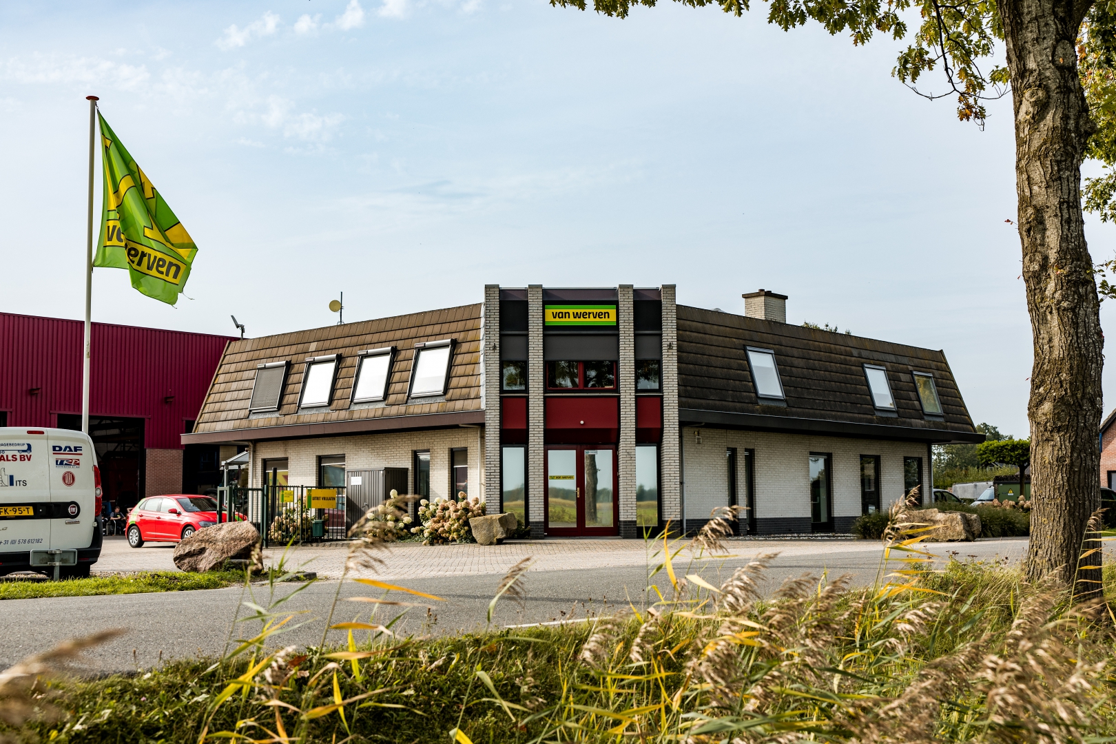 Kantoorpand van Van Werven met bedrijfsvlag, rode entree en een rode loods ernaast