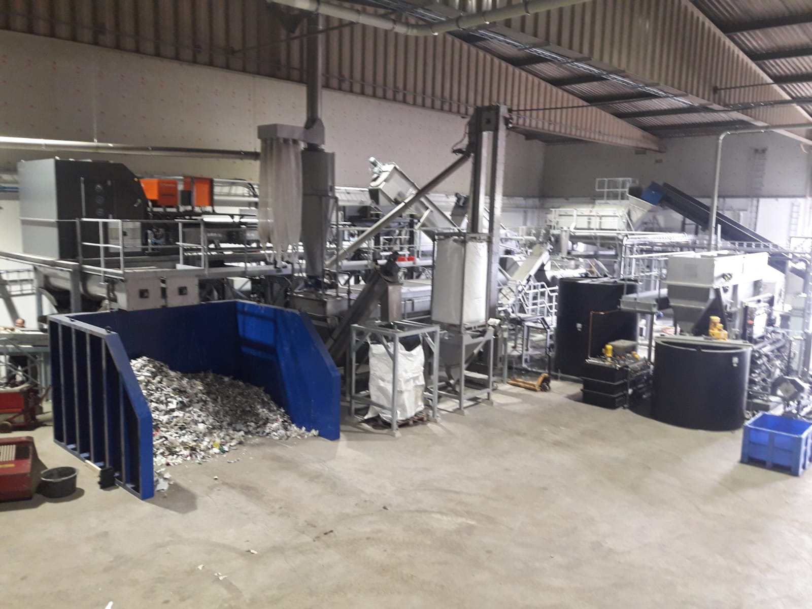 Productielijn voor kunststofrecycling in de hal, met big bags en snippers op de vloer