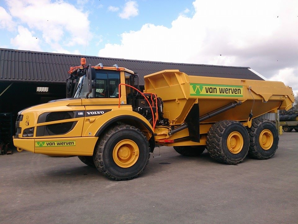 De knikdumper ECO 6x6 schuin van voren, geparkeerd voor de loods