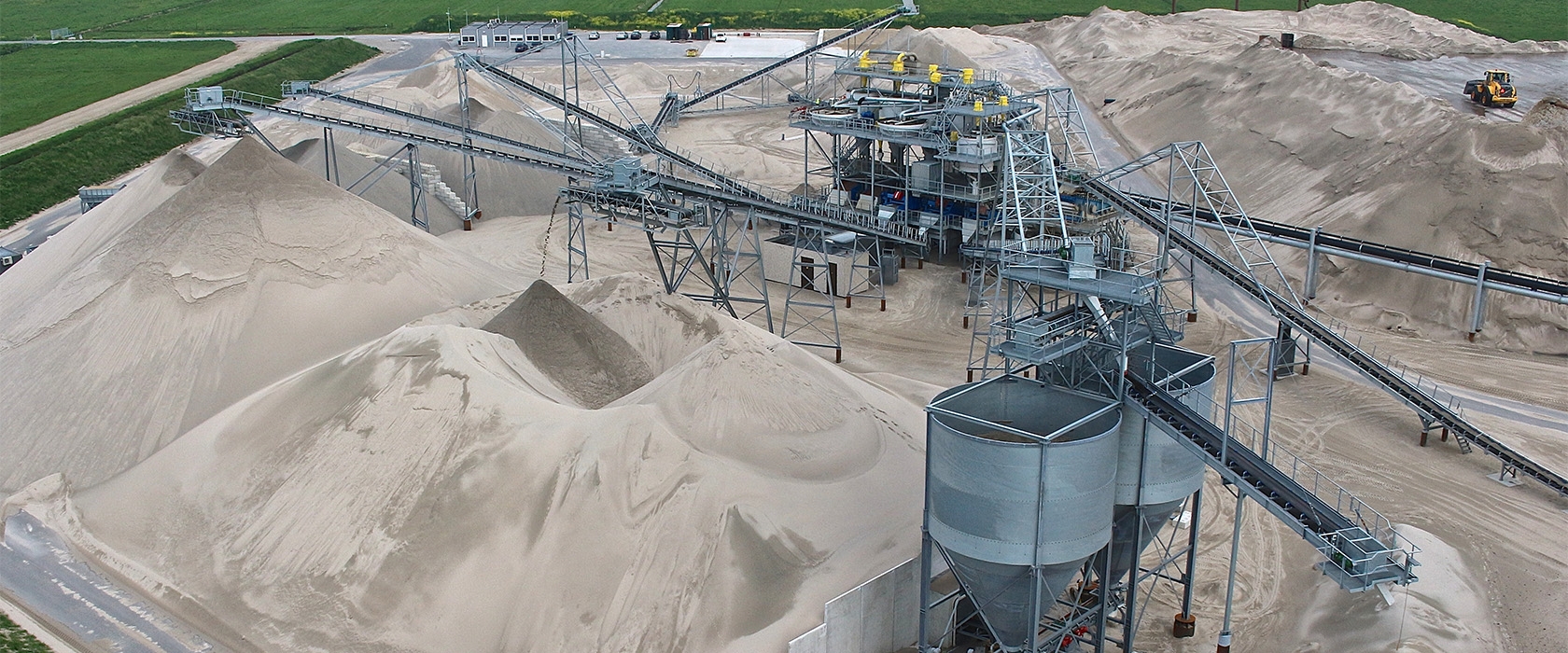 De zandwinplas bij Zeldenrust vanaf de oever, met de zuiger en de drijvende leiding