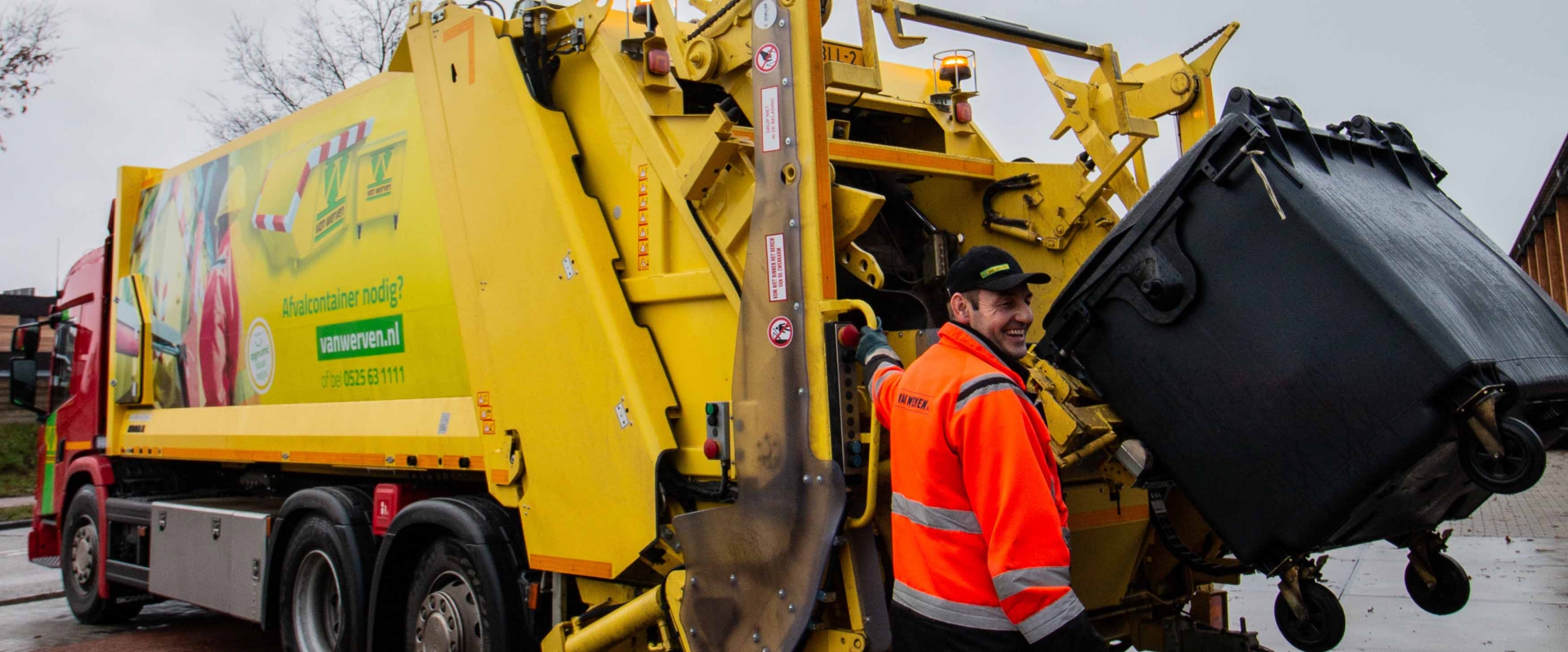 Belader leegt een rolcontainer in de gele kraakperswagen