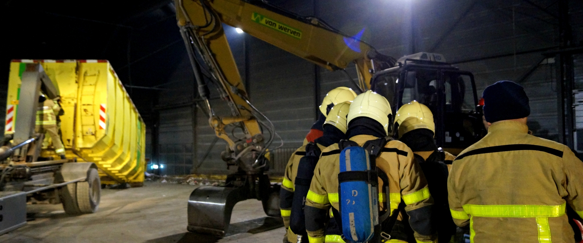 Brandweerlieden overleggen bij de overslagkraan tijdens de oefening in de hal