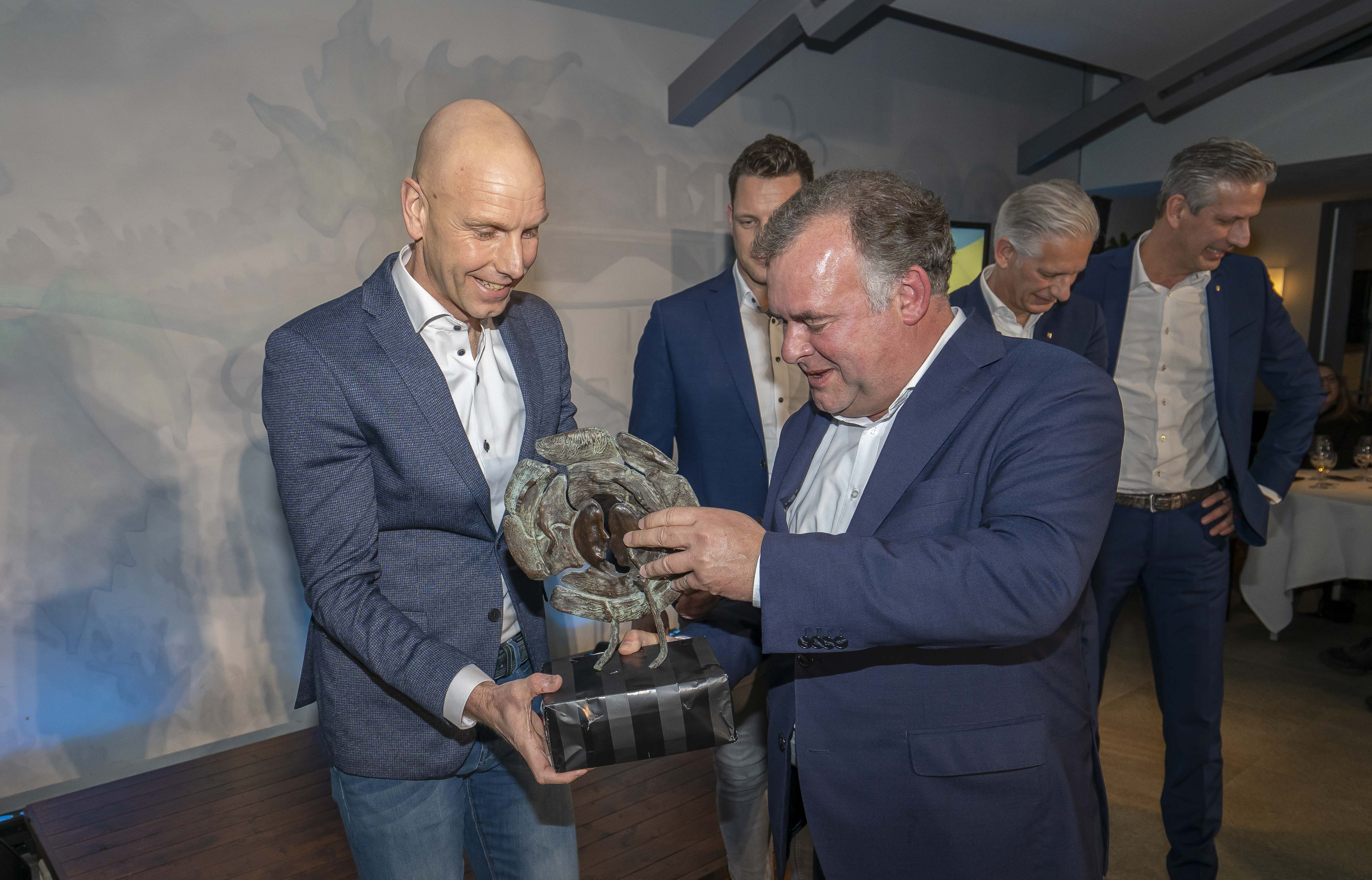 Twee mannen bekijken het bronzen kunstwerk van de award van dichtbij