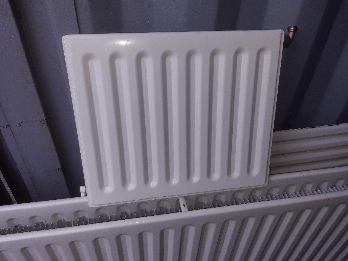 Kleine enkele paneelradiator, liggend op een grotere dubbele radiator