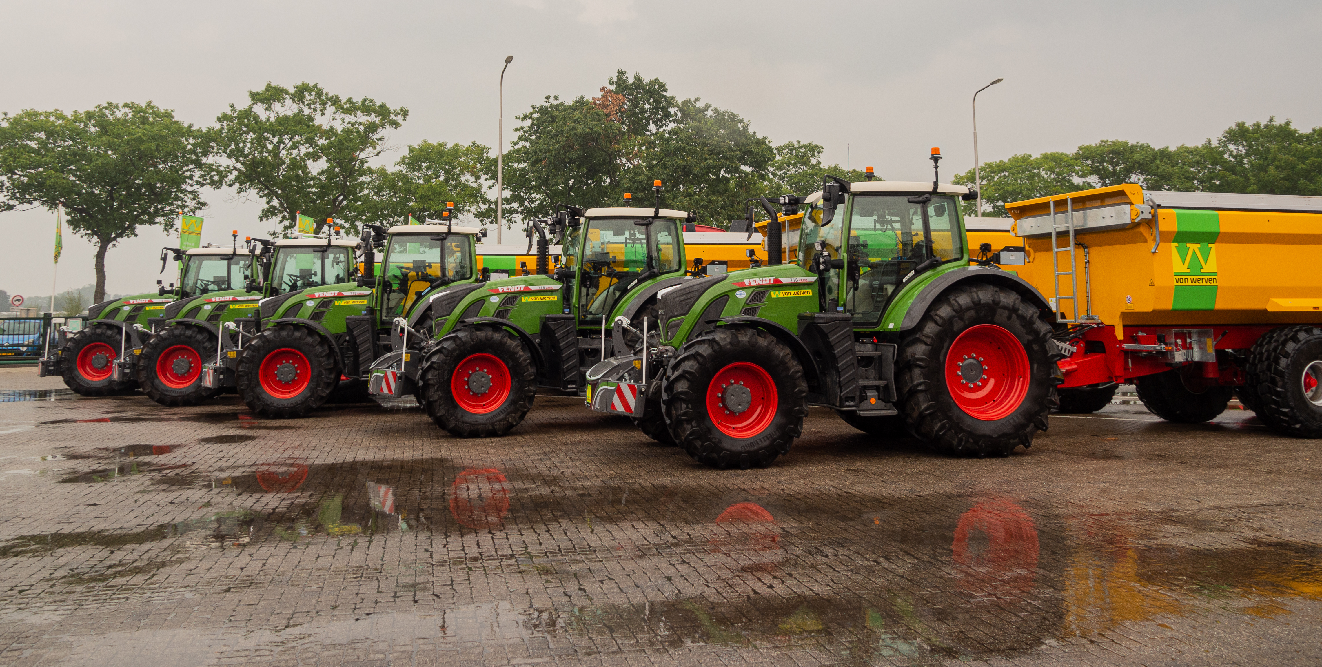 Vijf nieuwe Fendt-tractoren op een rij, met een gele kipwagen met Van Werven-logo