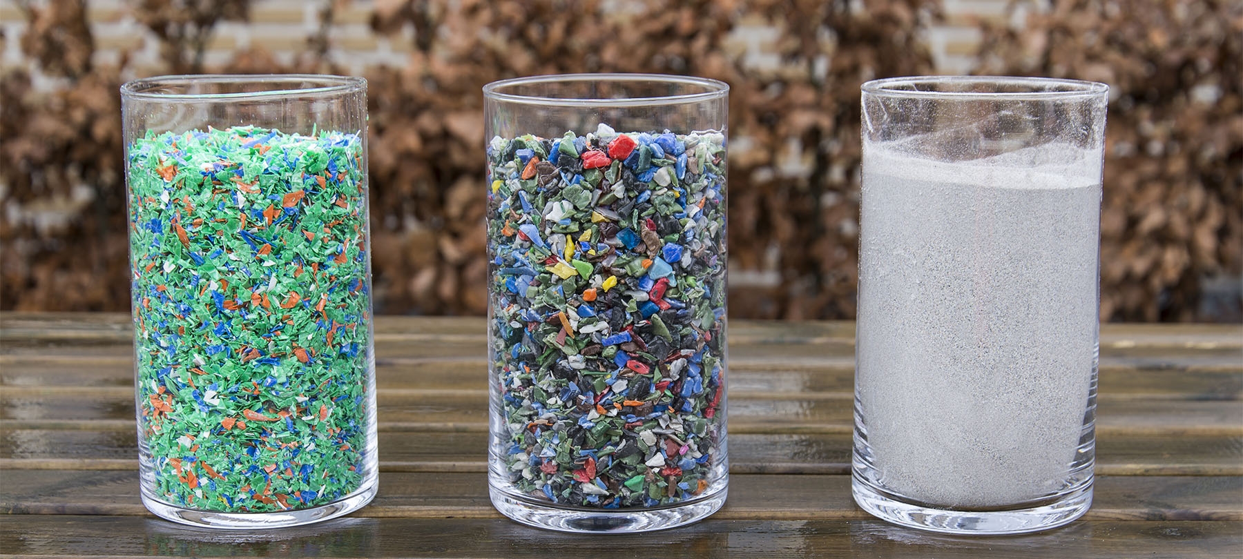 Drie glazen met kunststofrecyclaat: flakes, maalgoed en poeder
