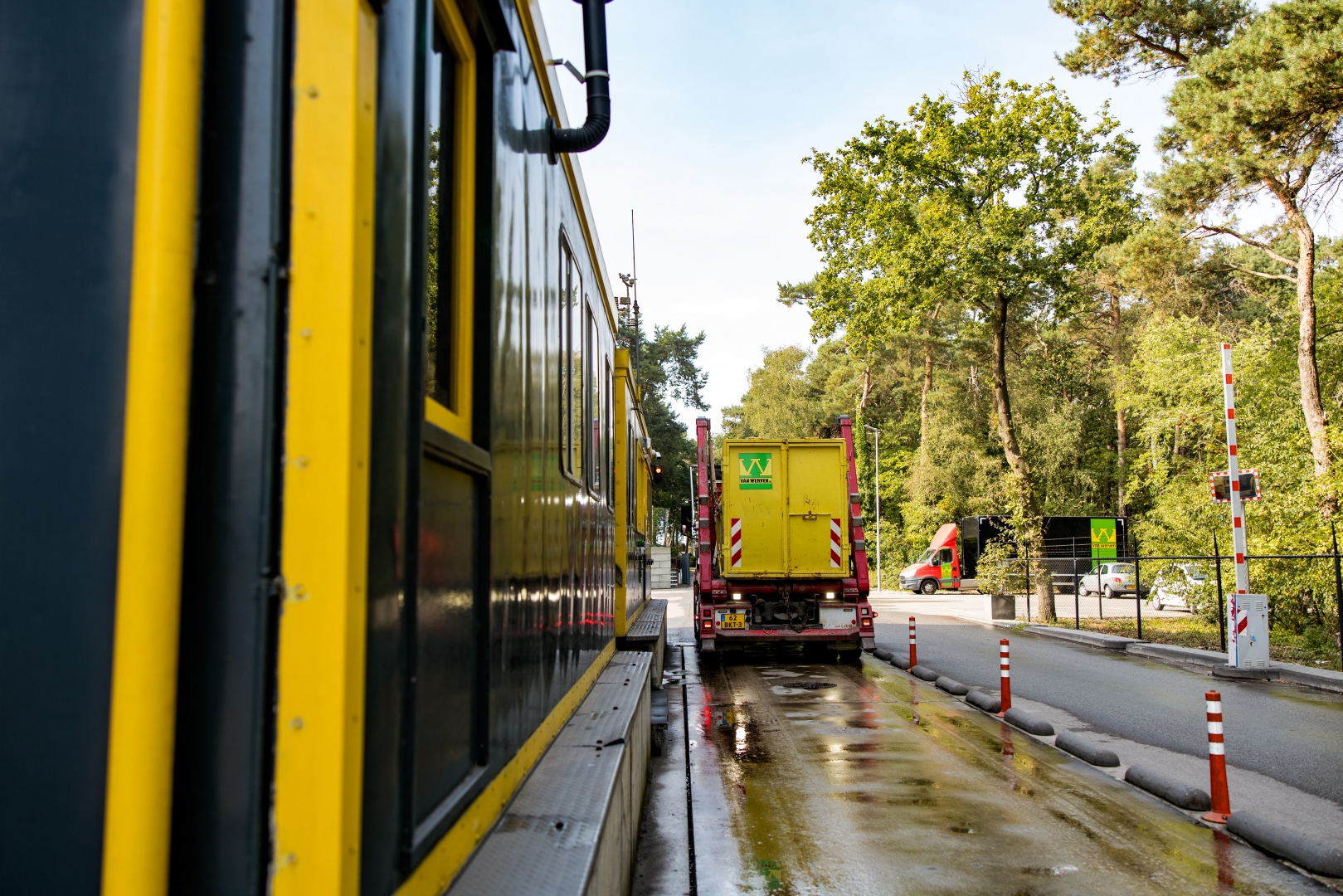 Een vrachtwagen met gele Van Werven-container staat op de weegbrug naast het geel-zwarte weegkantoor