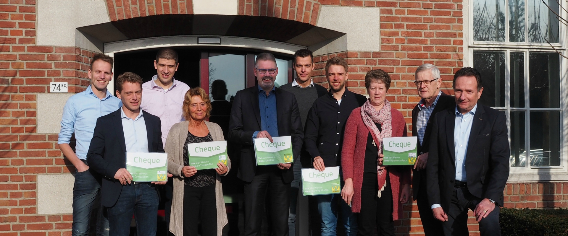 Vertegenwoordigers van de goede doelen poseren met hun cheques voor het kantoor