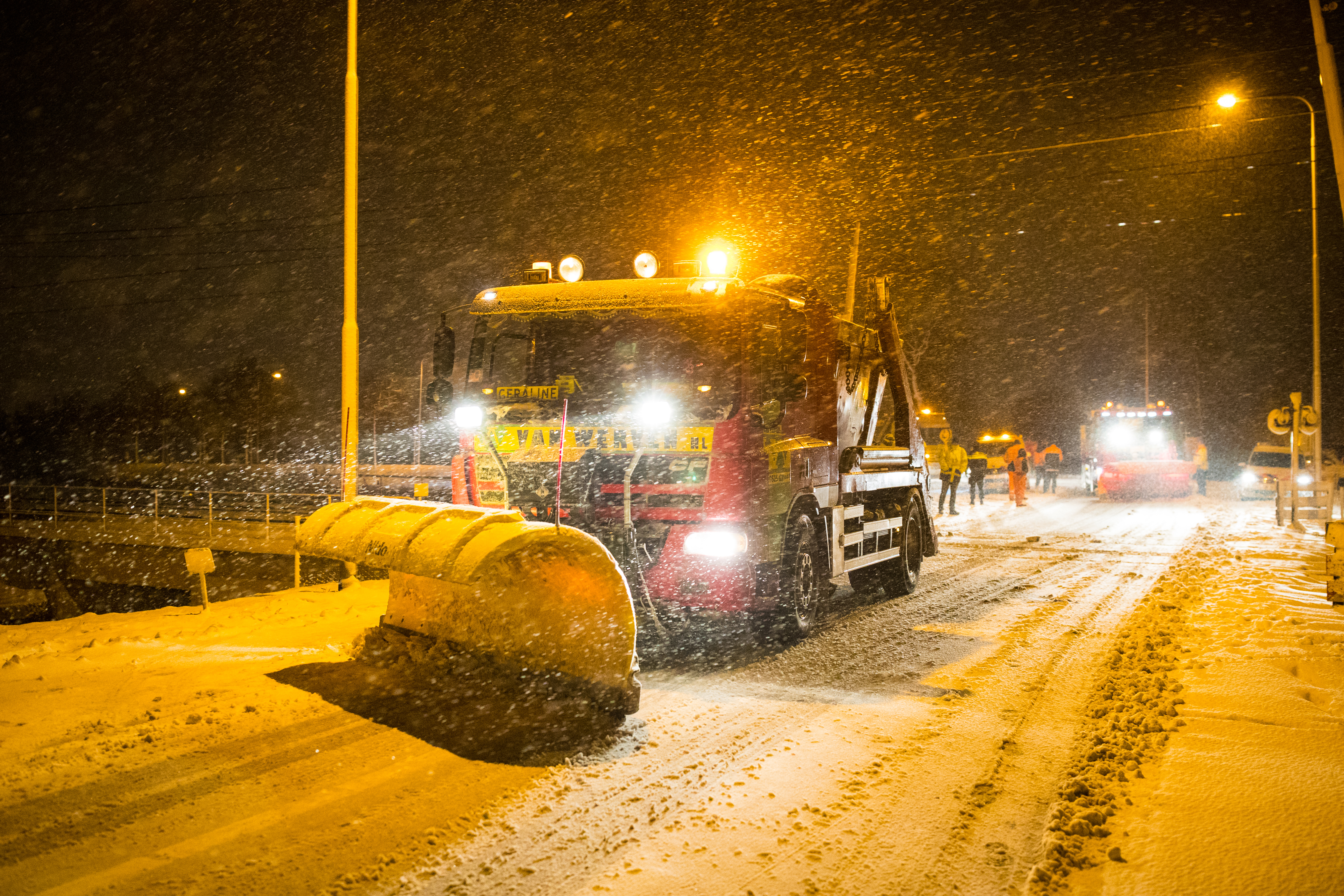 Sneeuwschuiver in het donker aan het werk tijdens hevige sneeuwval