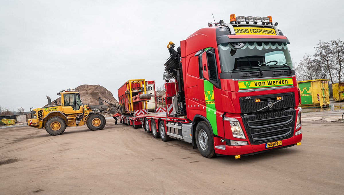 De Volvo FH-truck met dieplader op het terrein, met de gele Volvo wiellader ernaast
