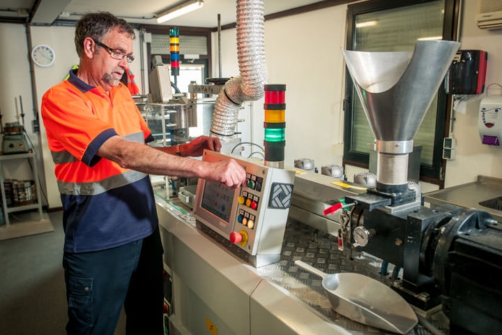 Een medewerker bedient het schakelpaneel van de kleine extrusielijn in het laboratorium