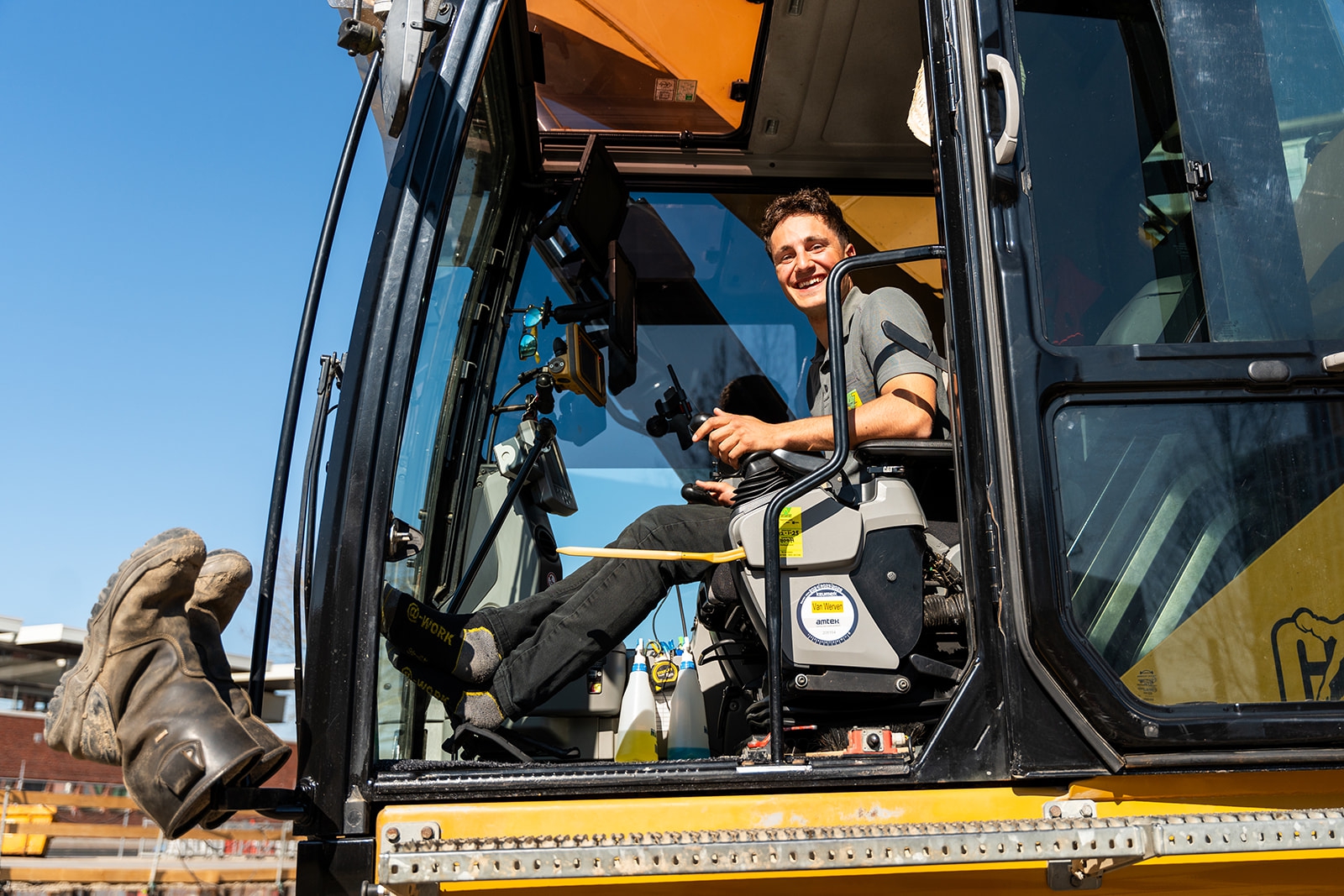 Lachende machinist in de cabine van zijn kraan bij Van Werven