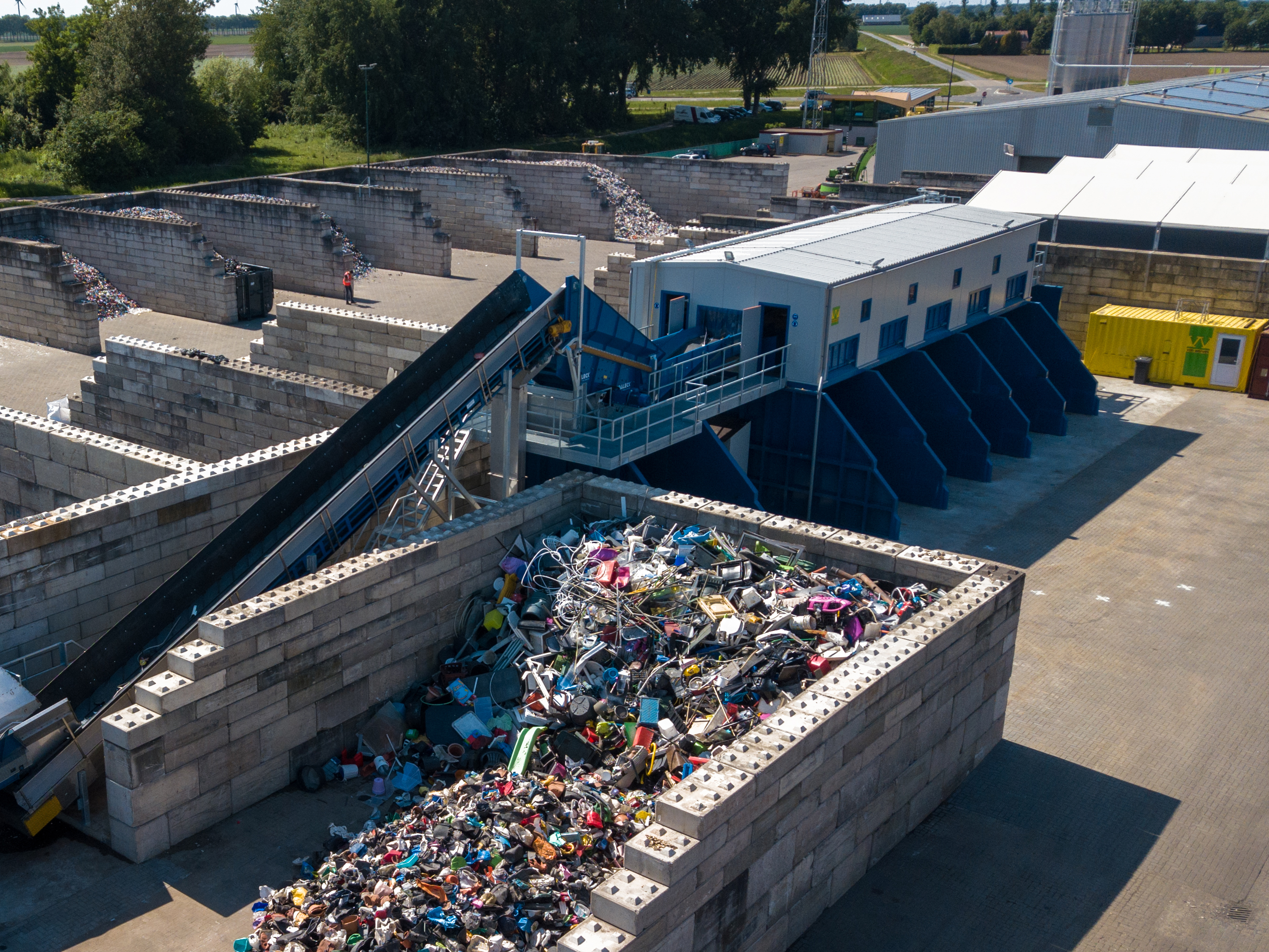 Luchtfoto van de sorteerinstallatie: een transportband voert gemengd hard plastic aan uit een vak van betonblokken