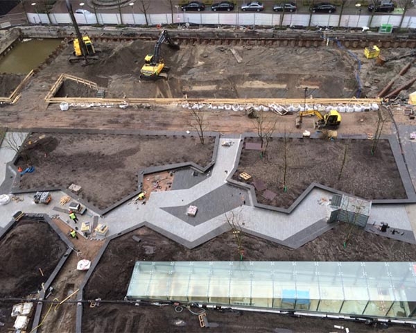 Luchtfoto van het plein in aanbouw: nieuwe bestrating in zigzagpatroon, plantvakken en het glazen dak van de fietsenstalling