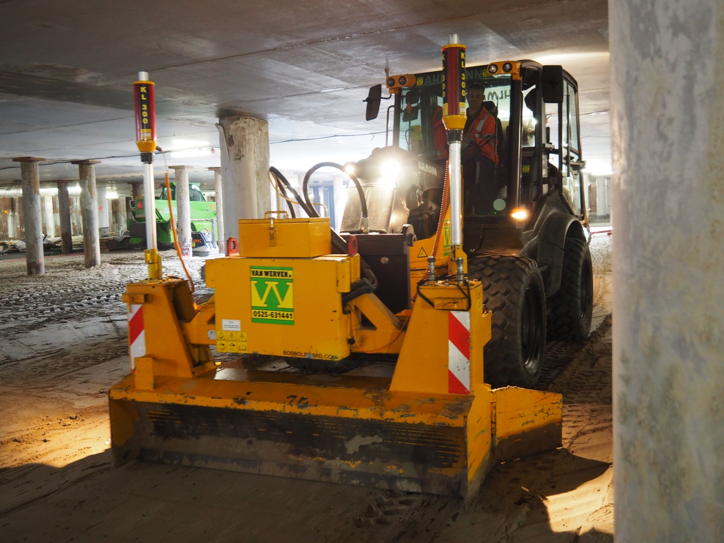 Een shovel met het lasergestuurde kilverbord van Van Werven egaliseert het zandbed onder het dek, tussen de betonnen palen