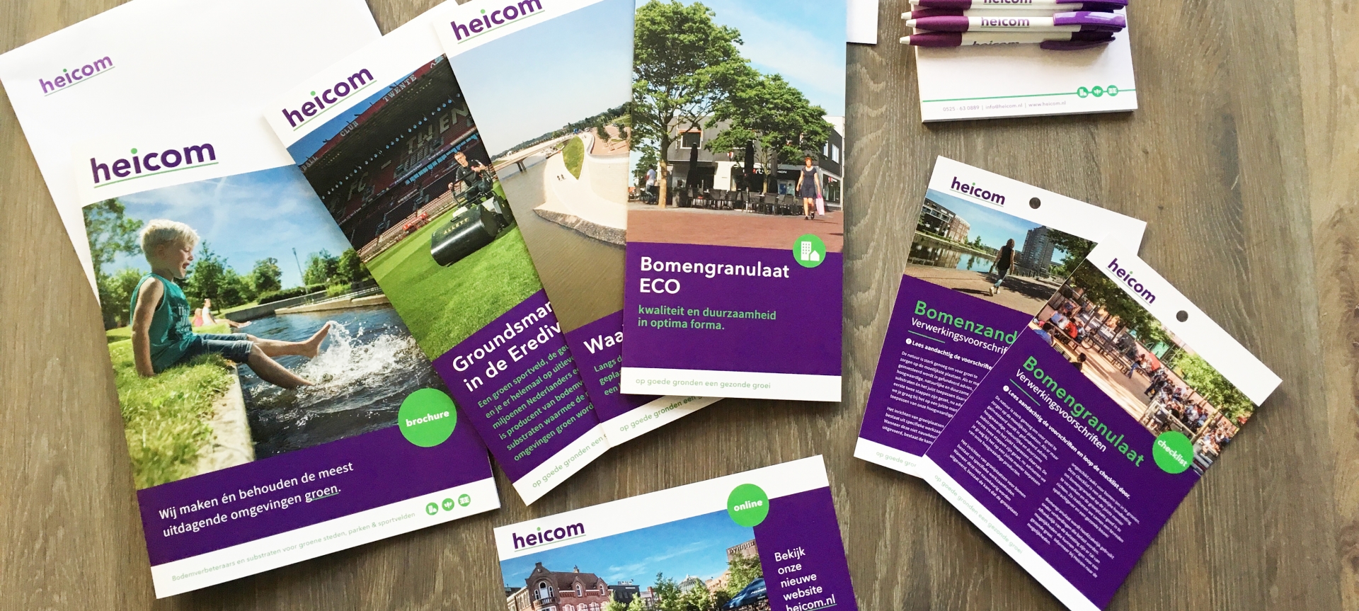 De nieuwe Heicom-brochures en -pennen op een houten tafel