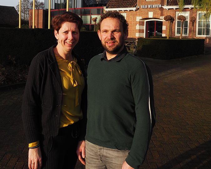 Gerben en zijn vrouw staan samen voor het hoofdkantoor van Van Werven in Oldebroek, in het lage avondlicht