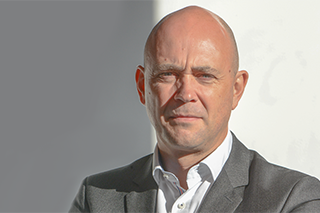 Portretfoto van een man in grijs colbert en wit overhemd