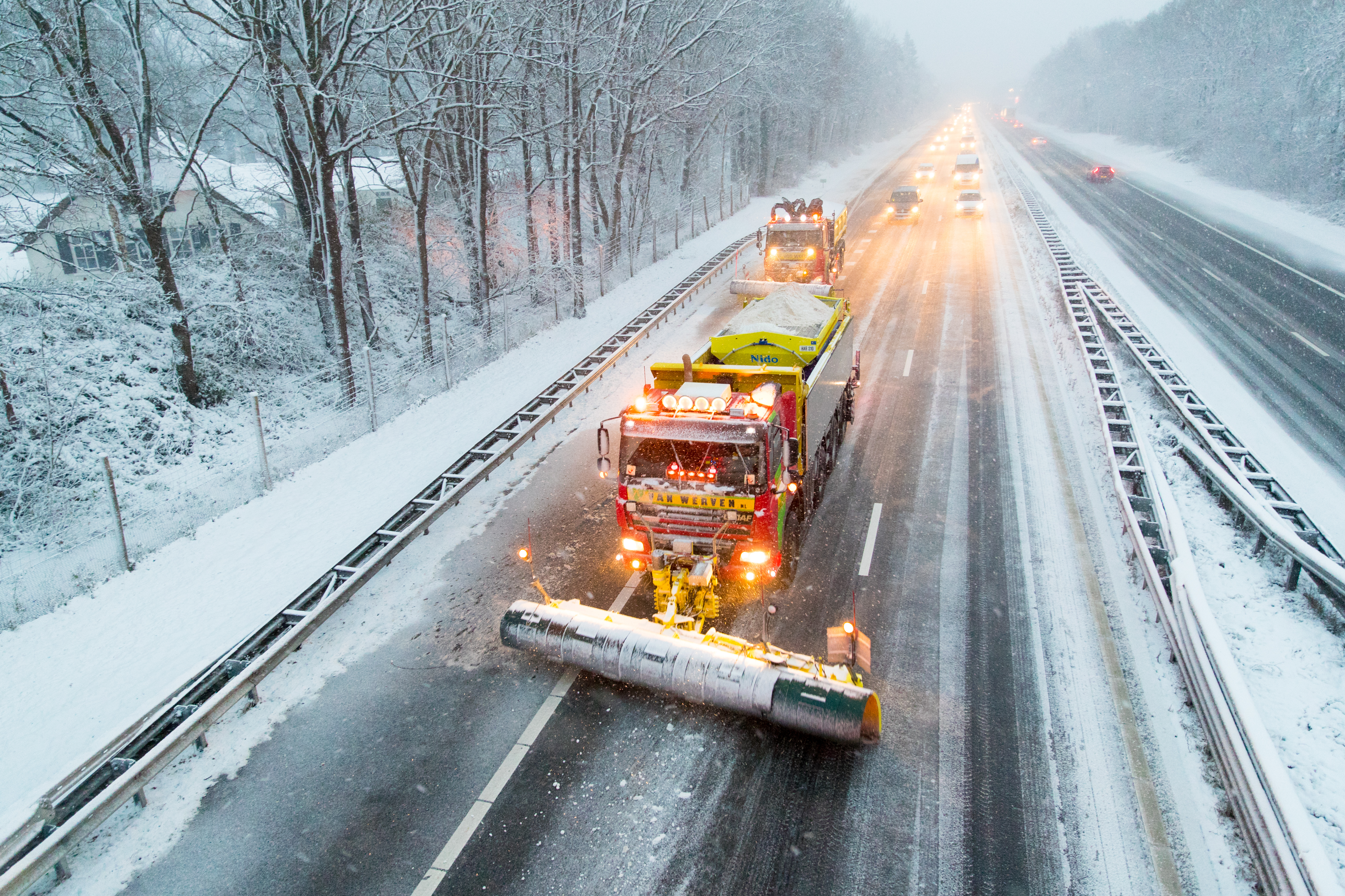 Sneeuwploeg en strooiwagen aan het werk op de winterse snelweg