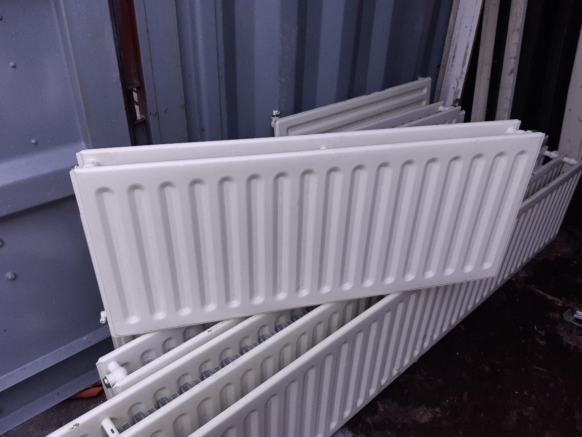 Lange dubbele paneelradiator, liggend op andere radiatoren
