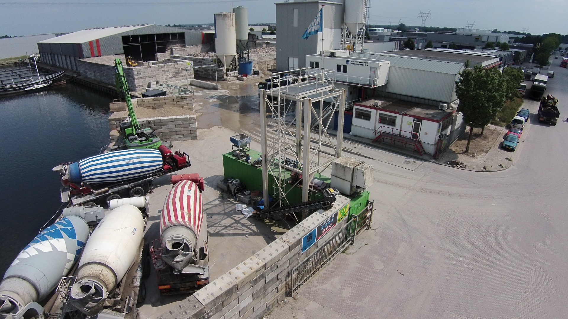 Luchtfoto van het terrein in Harderwijk met betonmixers, silo's en loodsen aan het water