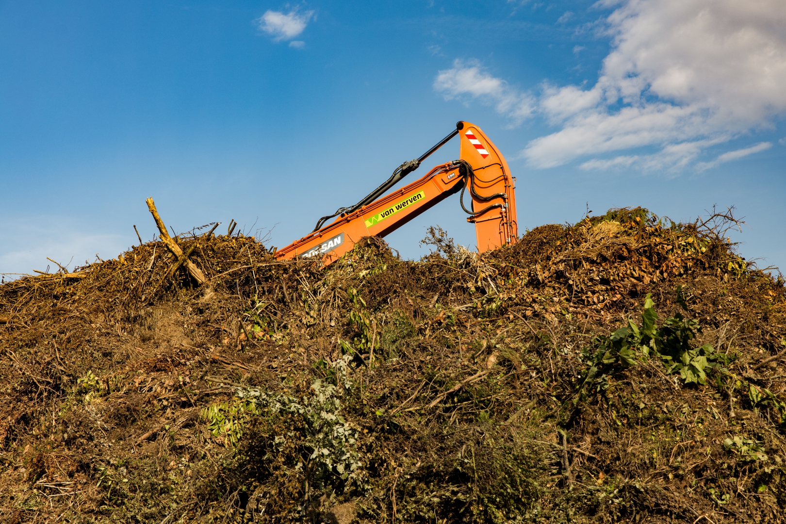 Kraanarm van Van Werven boven een berg groenafval op de recyclingvestiging
