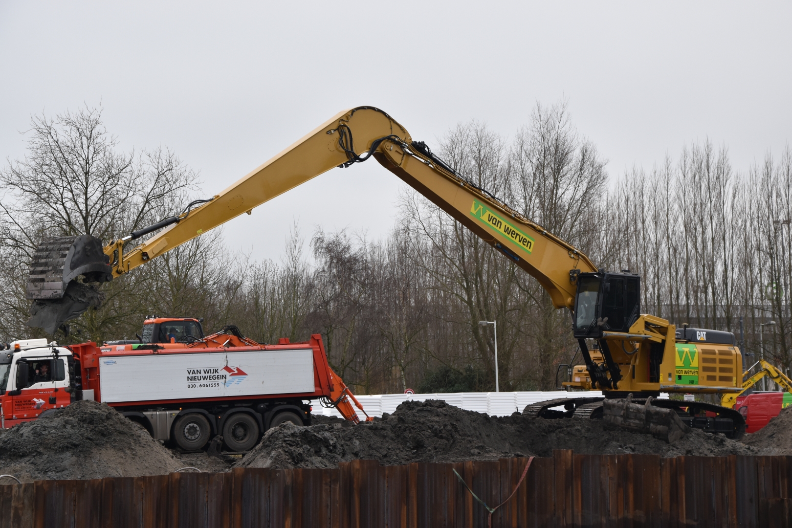 De rupskraan ECO Longreach laadt grond over de damwand in een kiepwagen