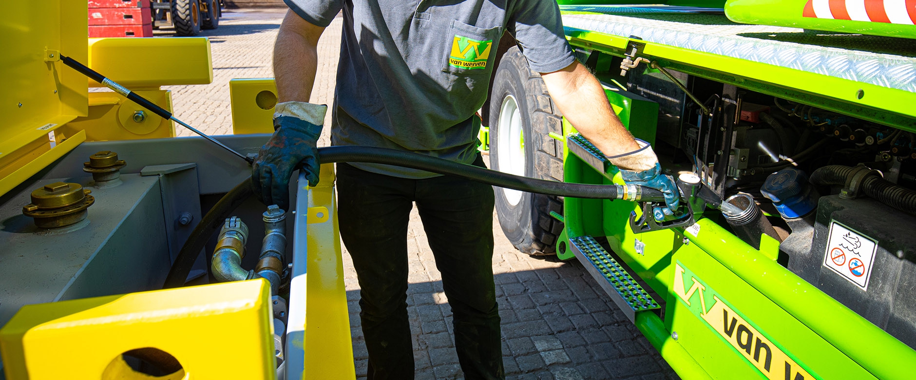 Een medewerker in Van Werven-shirt tankt een groene machine bij met een brandstofslang