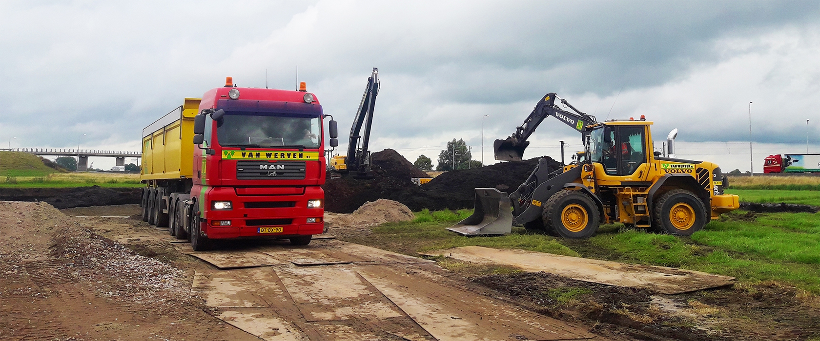 Vrachtwagen van Van Werven op rijplaten naast een Volvo wiellader en graafmachines die grond verzetten op het bouwterrein