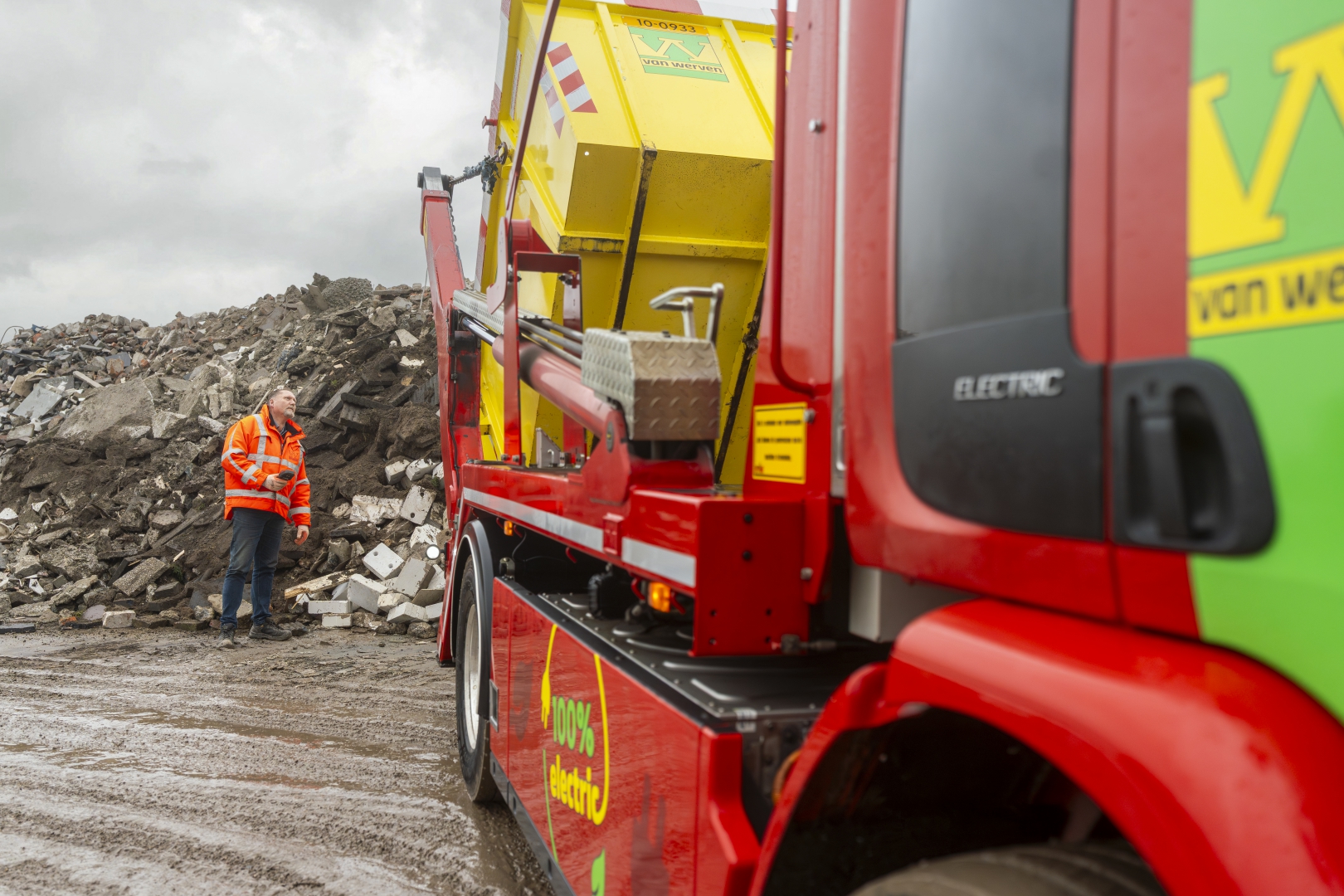 Chauffeur bij de elektrische portaalarmauto van Van Werven op een recyclinglocatie